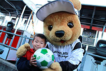 レクサス くま吉 LEXUS TEAM LeMans ENEOSパドック前で男の子のサッカーボールにサインをする