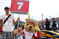トヨタ くま吉 平川選手のマシンの前でポーズをとる