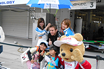 トヨタ くま吉 KONDO Racingのガレージ前でジェームス選手と記念撮影をする女の子2人と