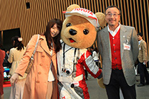 モータースポーツジャーナリストの高橋二朗氏と瀧口友里奈さんと写真を撮るトヨタ くま吉