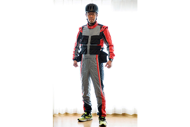 レーシングスーツがベースある。だがモータースポーツフォトグラファー特有の装備を付け加えられている。