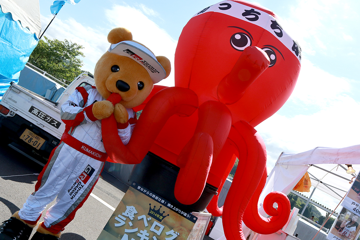 たこ焼きの人形と記念撮影するトヨタ くま吉
