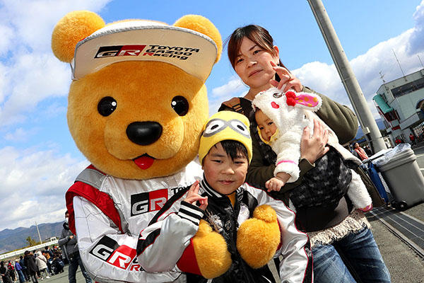 トヨタ くま吉 キャラクターのニット帽をかぶった男の子とうさぎのフードをかぶった赤ちゃんを抱いた女性と一緒に@ モースポフェス in 九州