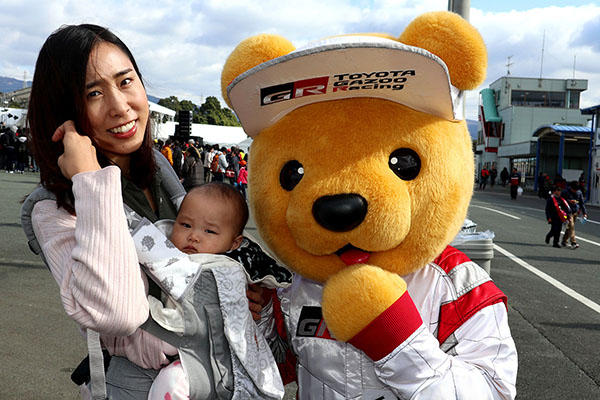 トヨタ くま吉 ライトグレーの抱っこひもで赤ちゃんを抱っこする女性と一緒に@ モースポフェス in 九州
