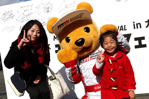 トヨタ くま吉 赤いダッフルコートを着た女の子とオフホワイトのトートバッグを腕にかけてる女性と一緒に@ モースポフェス in 九州